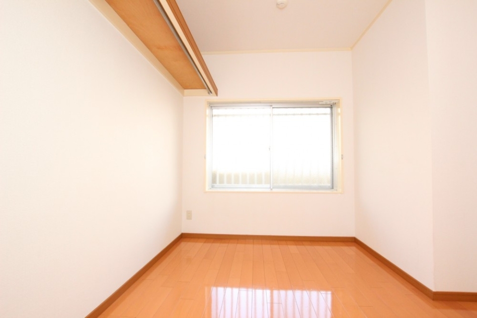 マンション通路側の6帖洋室。壁一面にハンガーパイプが備え付けられています