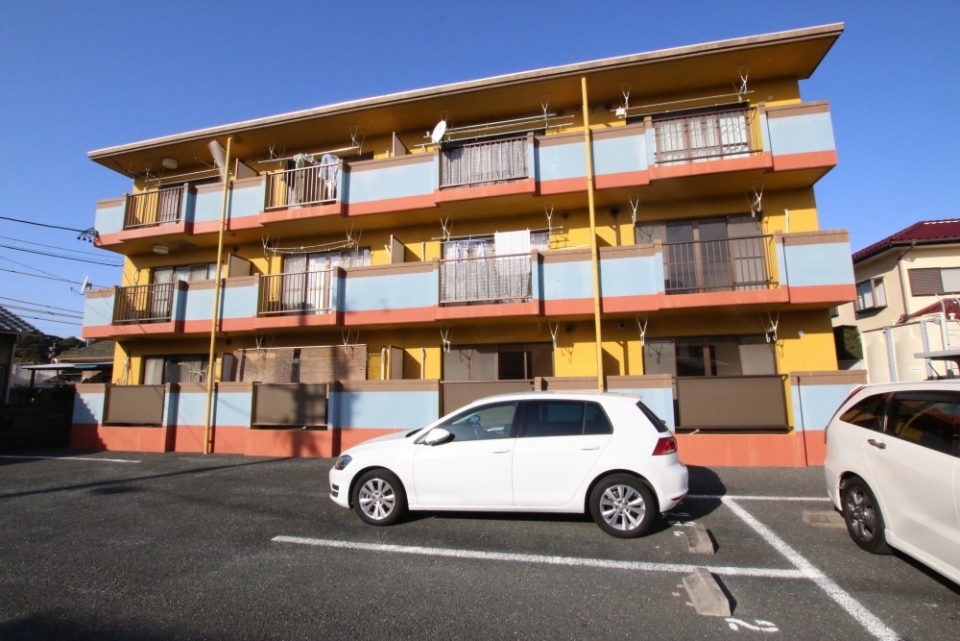 外観もイエロー×ブルーでおしゃれ。駐車場は広いが道は狭め。