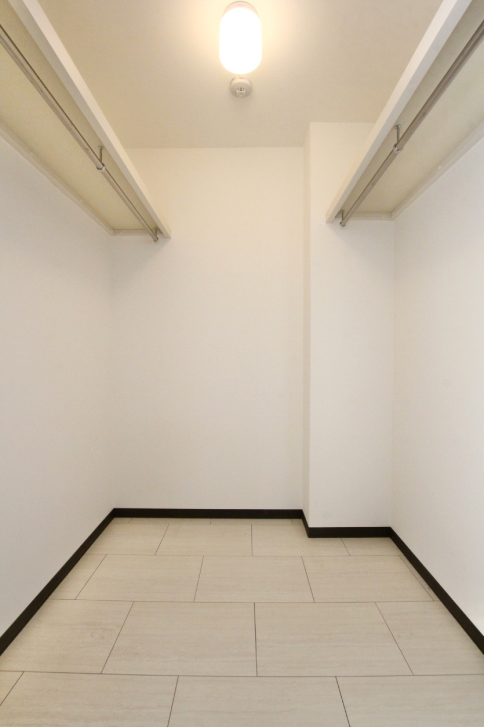 両壁にハンガーポールの付いた容量大のウォークインクローゼット