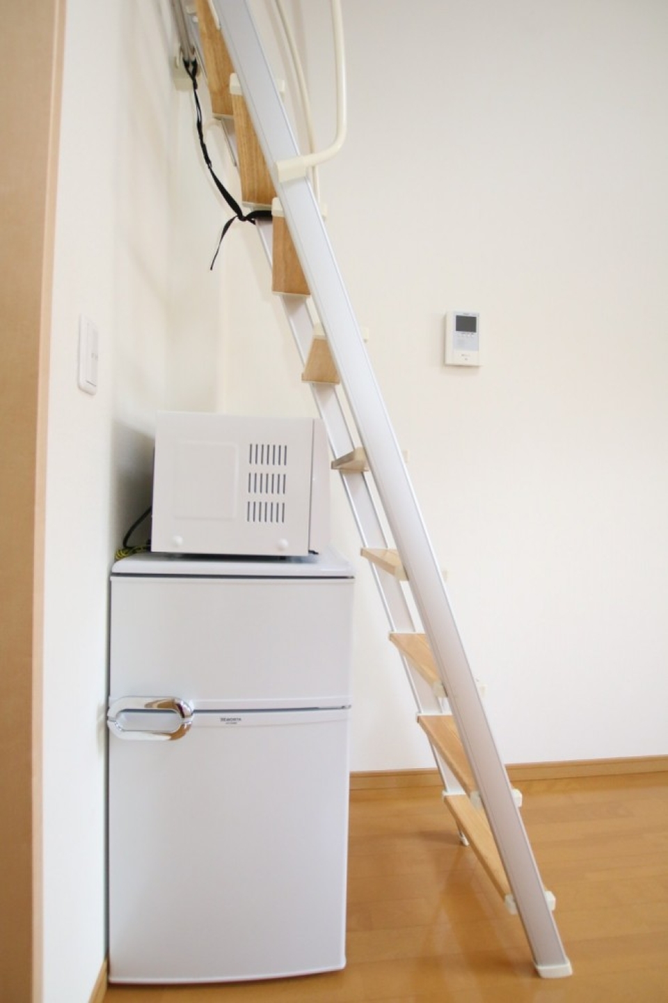 ロフトのハシゴしたに冷蔵庫と電子レンジ。この位置だと電子レンジが使いにくい。