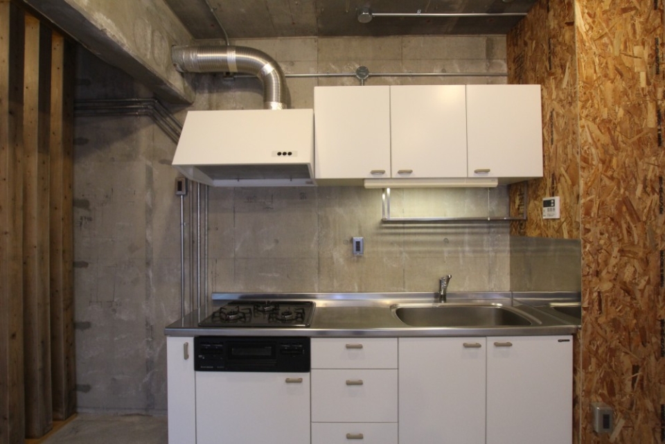 白いシステムキッチンが無機質な空間に映える。