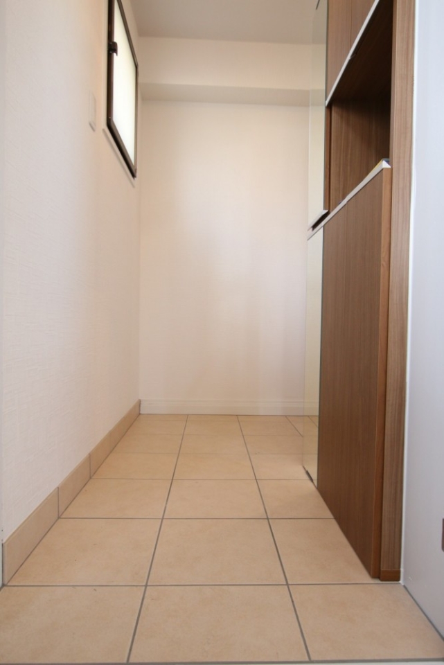 新品の鏡付きの靴箱と明るいタイルの玄関。