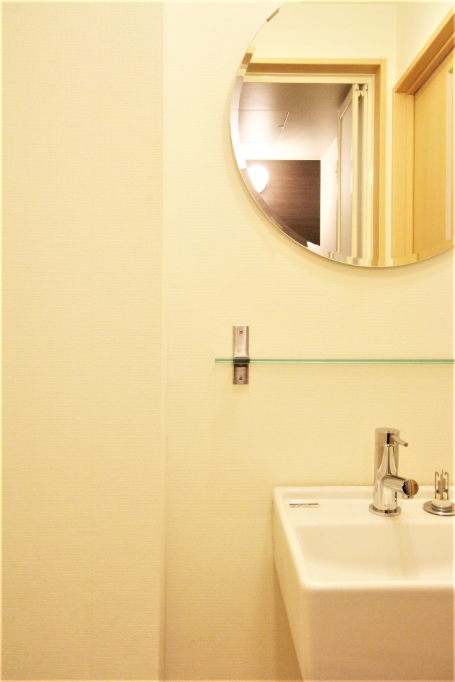 洗面スペース。丸い鏡に四角い洗面台、むき出しの配管がおしゃれ。