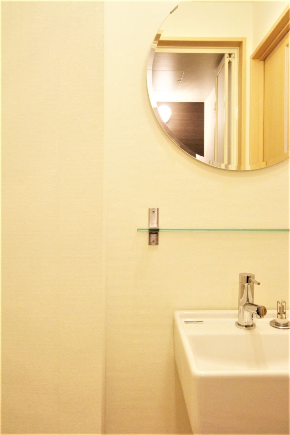 洗面スペース。丸い鏡に四角い洗面台、むき出しの配管がおしゃれ。
