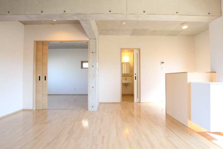 正面からキッチン、洋室を見渡す。白い扉は水回りにへ続く。