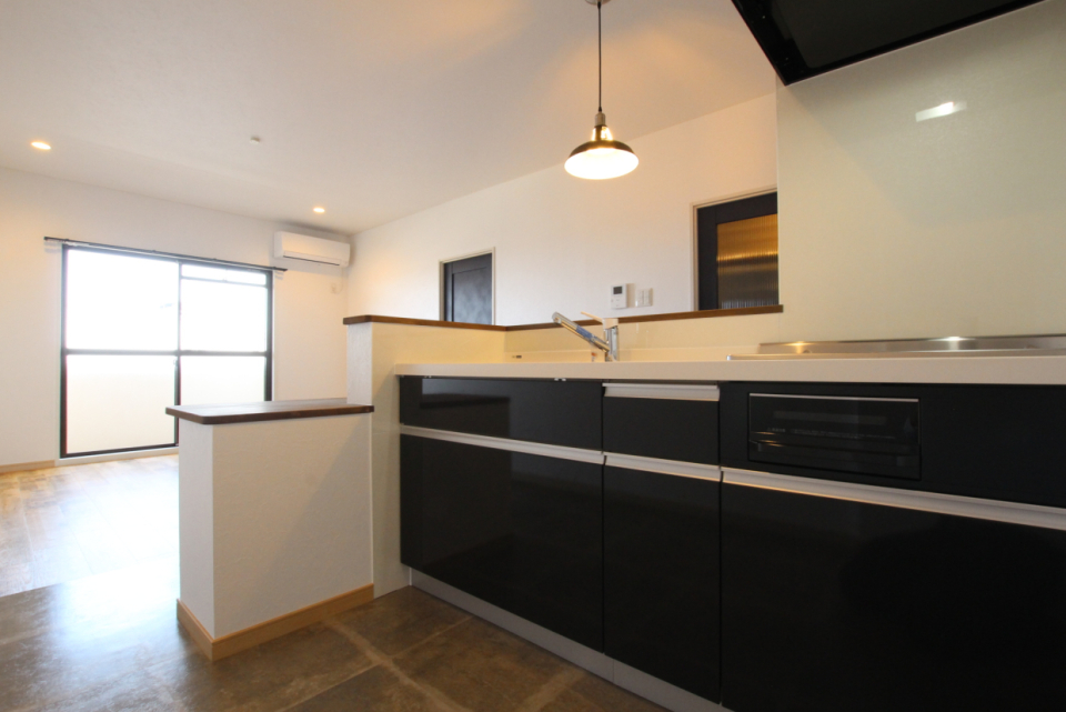 ダークカラーのシステムキッチン。ペンダントライトが似合う