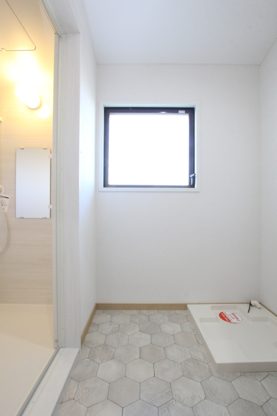 脱衣所は薄いグレーのヘキサゴンタイル風のフロア。大きな換気窓あり