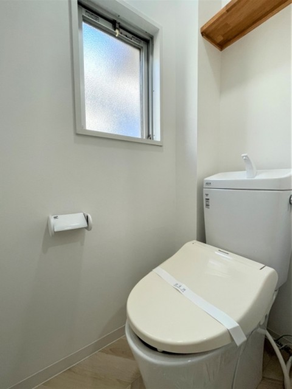 窓付きのトイレ。頭上に棚があります。