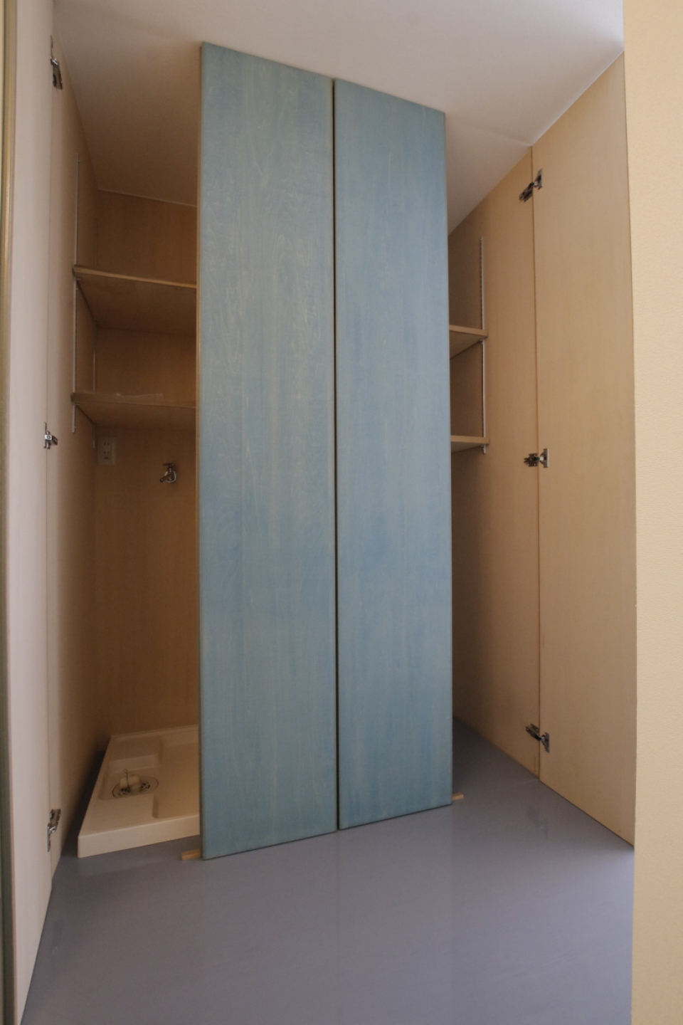 通路にある収納と洗濯機置き場。お揃いの扉の色