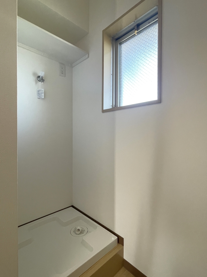 玄関入ってすぐ右手側には洗濯機置場、その上には棚もあります