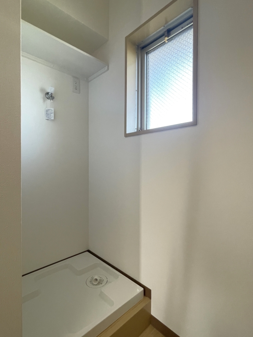 玄関入ってすぐ右手側には洗濯機置場、その上には棚もあります