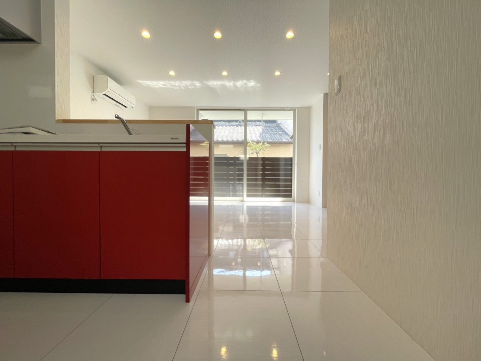 白色のリビングに赤色のキッチンが映えています。