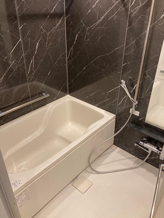 黒い大理石調に囲まれた浴室。