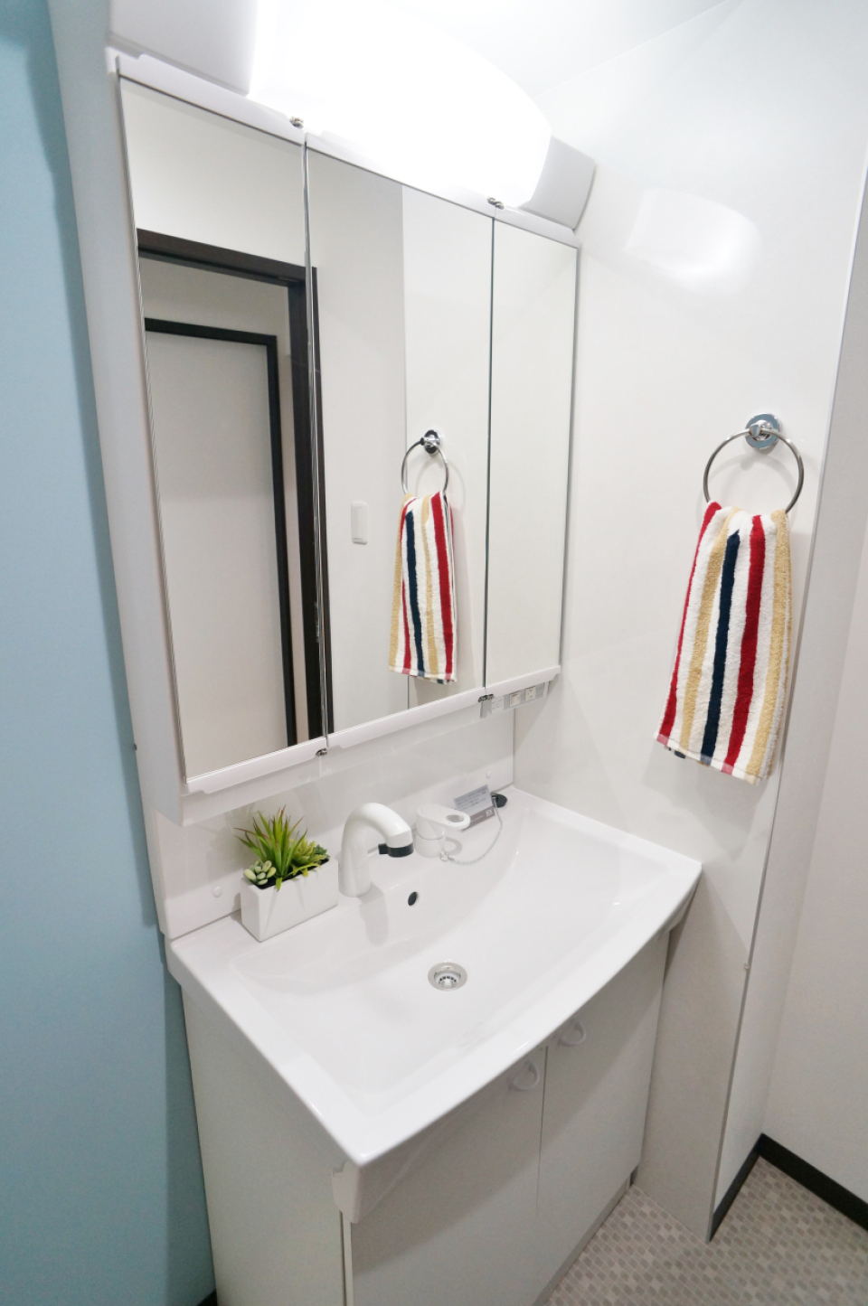 水色の壁紙と洗面の白の調和が素敵です