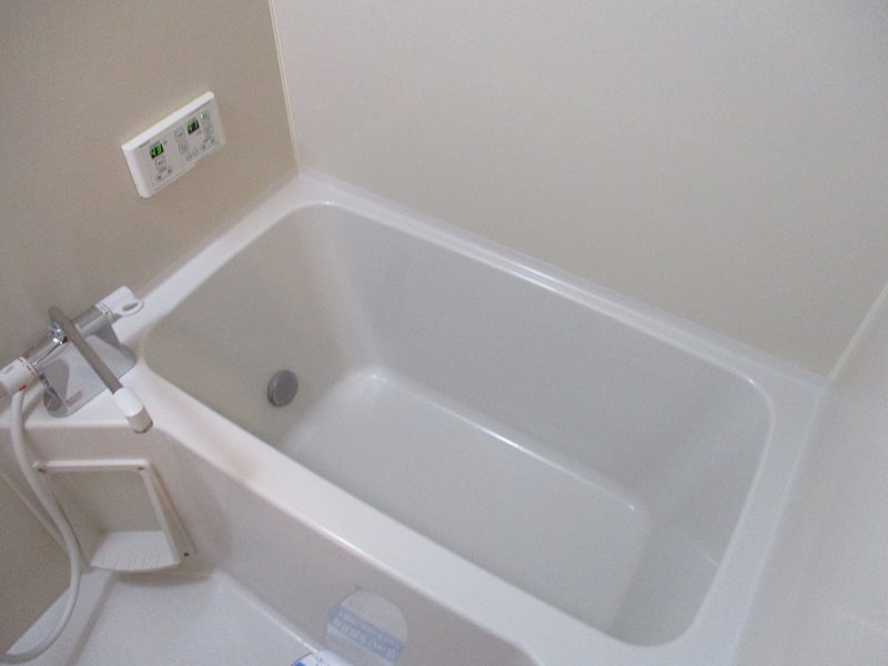 壁も床も真っ白なバスルーム。給湯リモコンはキッチンにも付いています。