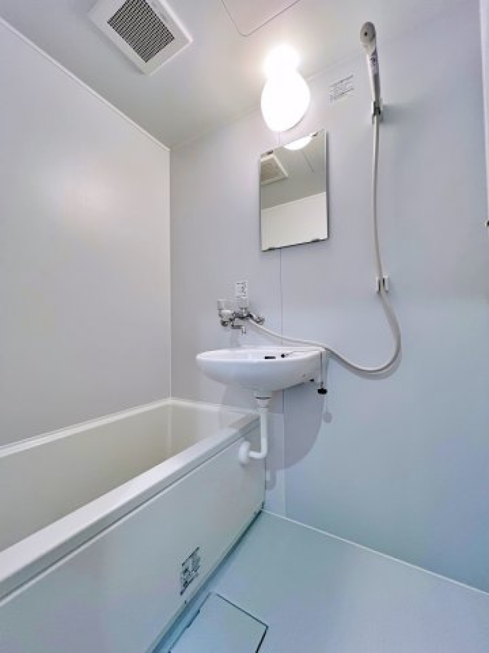 白でまとめられた浴室。浴槽と洗面台はお隣同士。