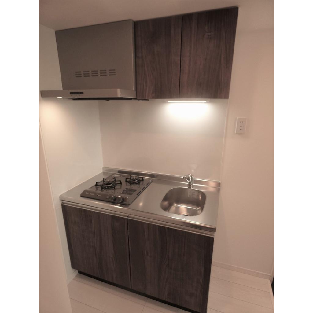 レンジフードが付いた２口コンロ。シンクより大き目のまな板で調理スペースを確保できそう。