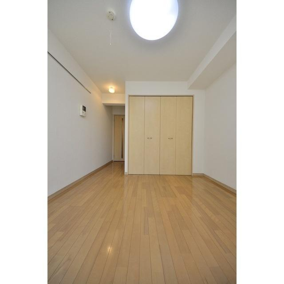 ナチュラルなカラーのフロアと建具に白い壁の洋室です。