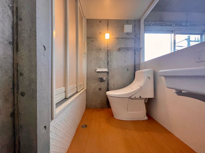 扉を開けると洗面台・トイレと続いています。居室同様にコンクリをそのまま活かしており、統一感があります。