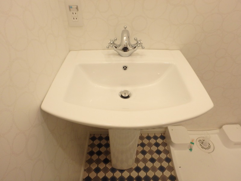 洗面台・室内洗濯機置き場です。蛇口の形と床のデザインに目を惹かれますね。