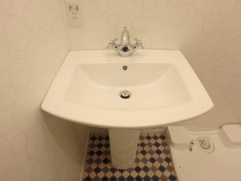 洗面台・室内洗濯機置き場です。蛇口の形と床のデザインに目を惹かれますね。