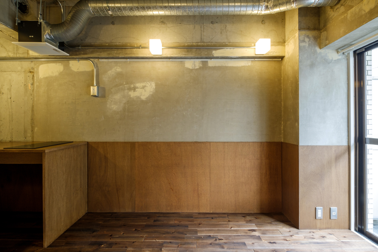 コンクリートとラワン合板で仕上げられた2トーン壁