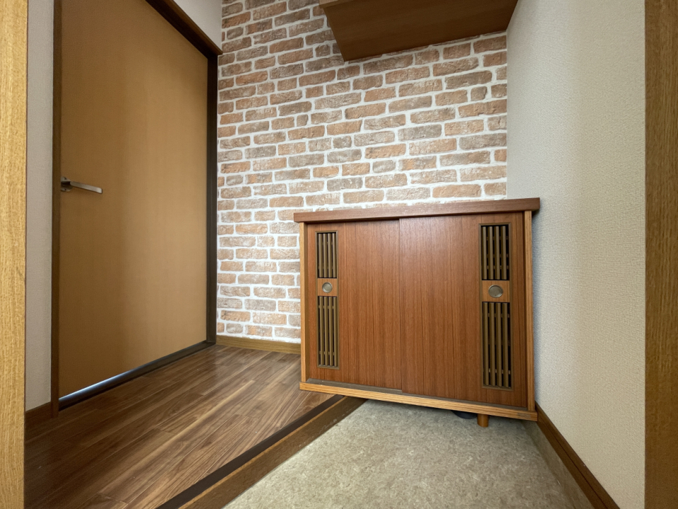 玄関はレンガチックなアクセントクロスがお出迎え。