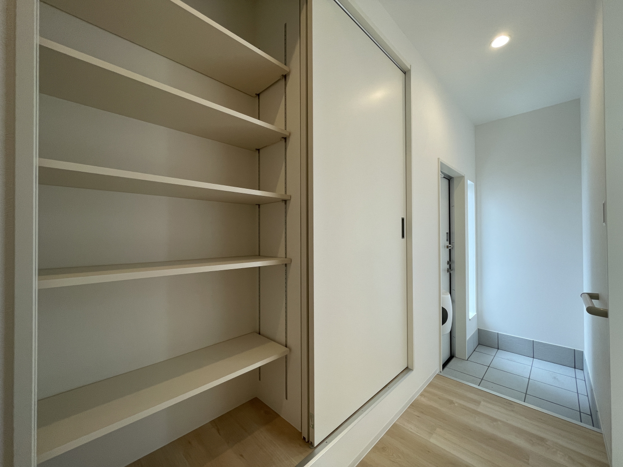 玄関には靴箱を兼ねた大きめの収納が。引き戸をずらすと右手にも同じ棚が現れます！