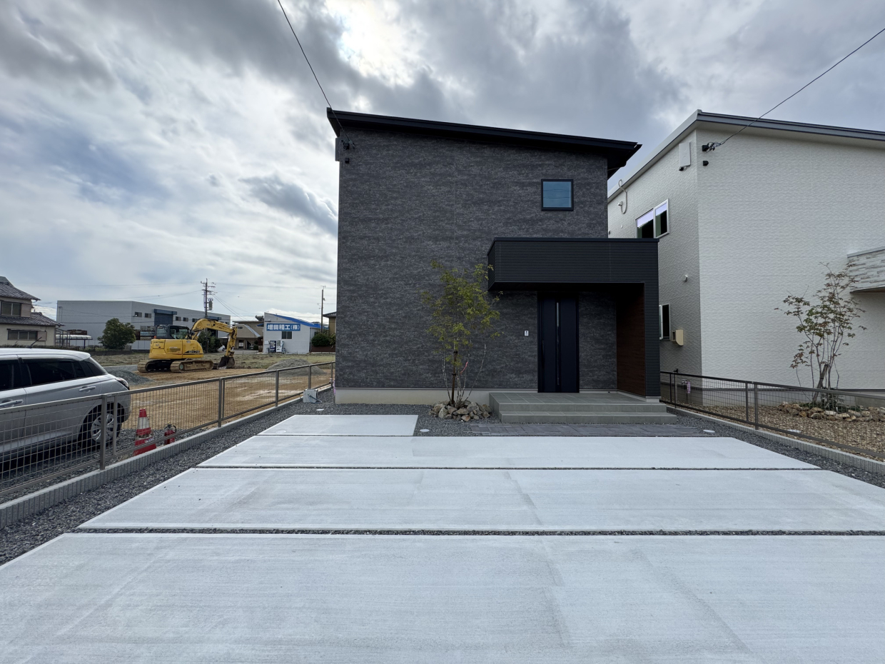 黒い外観とコンクリート打設の駐車場のコントラストが映える